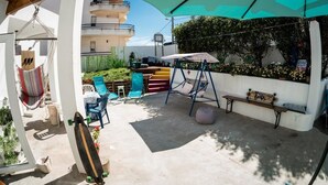 Un patio con una hamaca, una patineta, mobiliario exterior y un columpio.