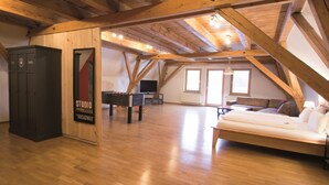 Ein geräumiges Loft mit Holzbalken, einer Couch, einem Kicker und einer dunklen Kommode mit dem Aufdruck "STUDIO PHOTO BROADWAY".
