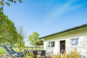 A house with a patio, two lounge chairs, and a table. - Hotel Hofgut Tiergarten (Aulendorf)