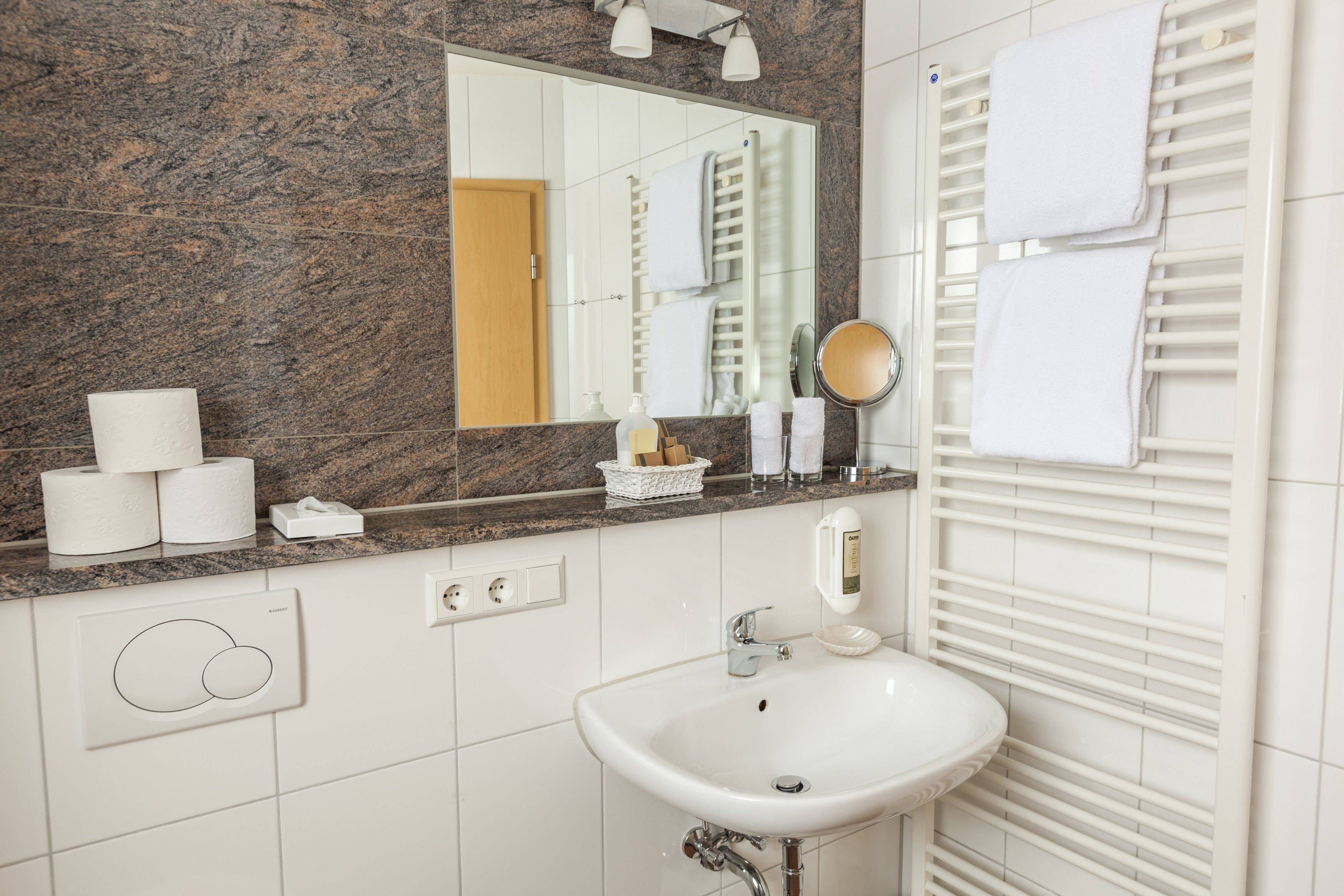 A bathroom with a marble countertop, a sink, a mirror, and a towel rack.