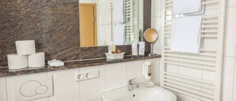 A bathroom with a marble countertop, a sink, a mirror, and a towel rack.