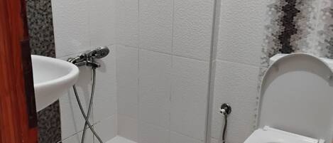 A bathroom with a toilet, sink, and shower.