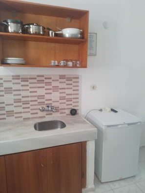 A kitchen with wooden cabinets, a tiled backsplash, a stainless steel sink, and a white refrigerator.