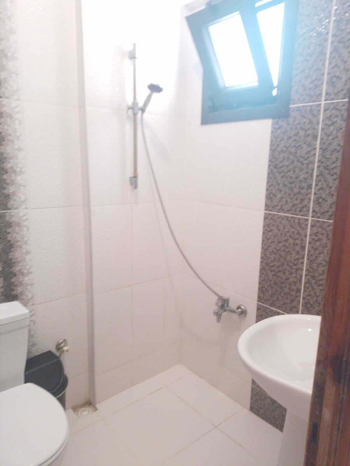 Un baño pequeño con inodoro, ducha y lavamanos.