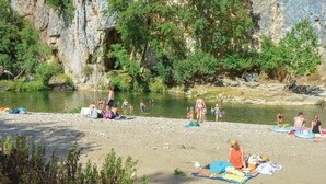 Ein Flussufer mit badenden und entspannenden Menschen.