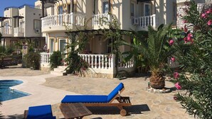 Ein Hotel mit Pool, Sitzgelegenheiten im Freien und einem Blumengarten.