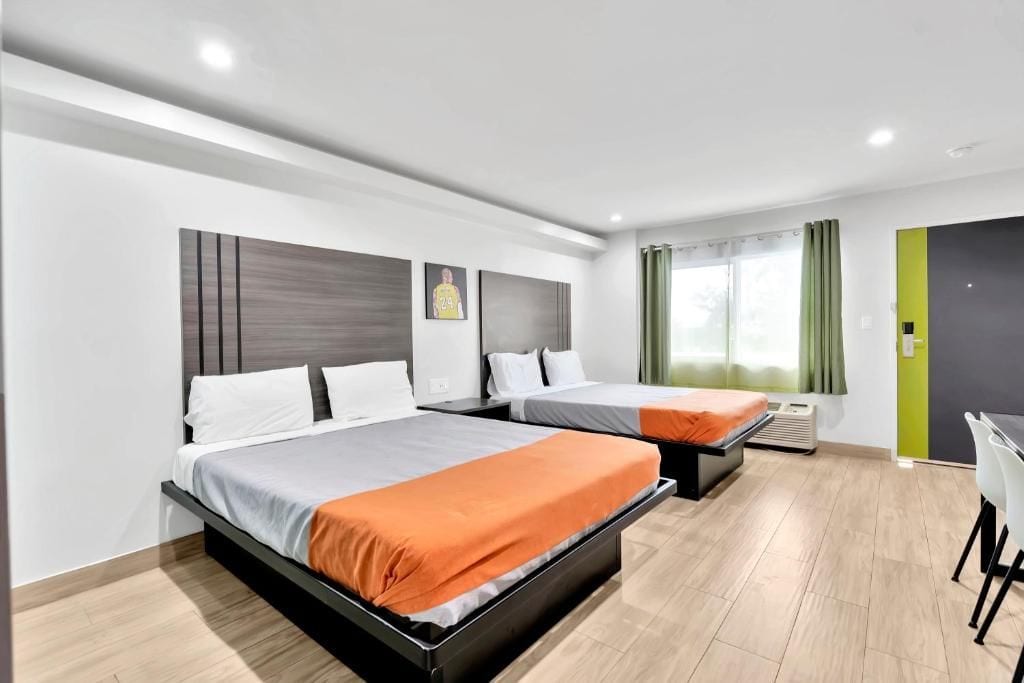Ein Hotelzimmer mit zwei Betten, einem Schreibtisch und einem Stuhl.