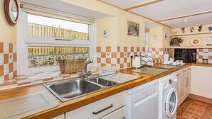 A kitchen with a wooden countertop, stainless steel sink, white cabinets, a washing machine, and a window with a view of a balcony. - 3 bedroom accommodation in Grinton, near Reeth (Grinton, near Reeth)