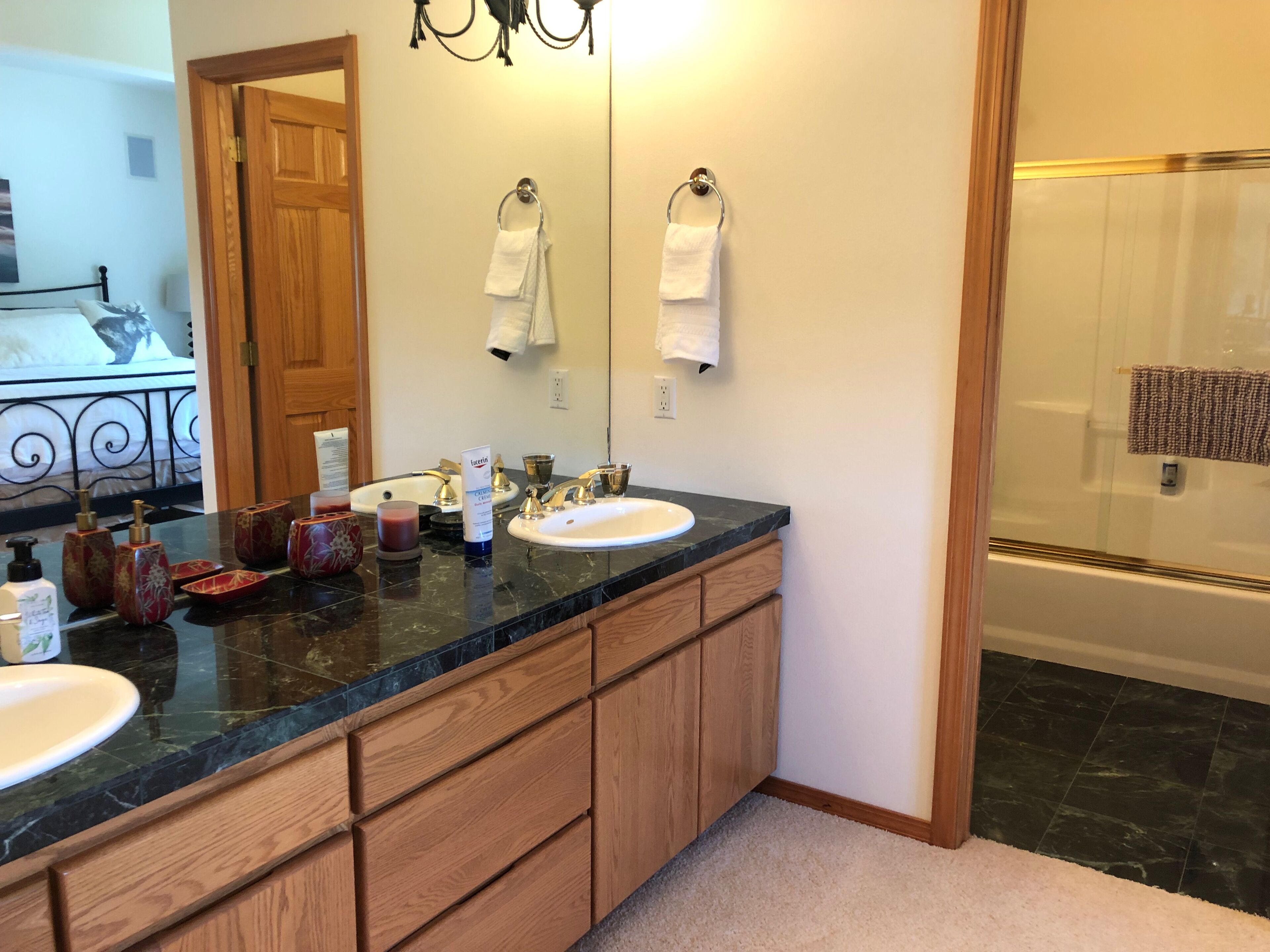Une salle de bain avec un meuble-lavabo à deux vasques, des armoires en bois, un miroir et un espace douche.