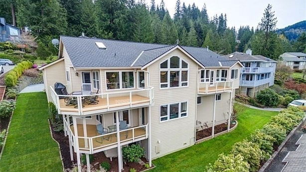 Een tweelaags huis met een balkon, een overdekte veranda en een verzorgd gazon.