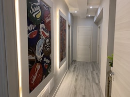 Um corredor com piso claro, paredes brancas e uma porta no final.