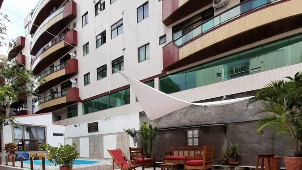 Un edificio de varios pisos con balcones, mobiliario exterior y una zona de piscina.