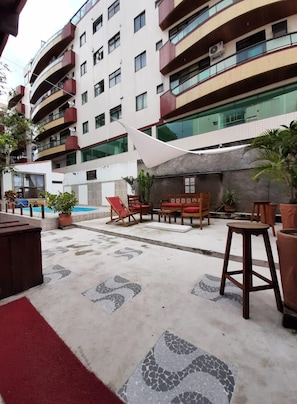 A multi-story building with balconies, outdoor seating, and a pool area.