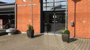 The exterior of a building with a large glass entrance, a sign reading "RIDDING CENTRE," and two potted plants in front.