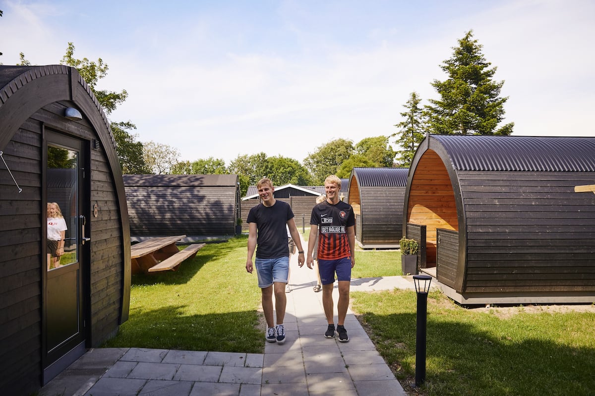 A row of modern, curved-roofed cabins with a paved walkway between them.