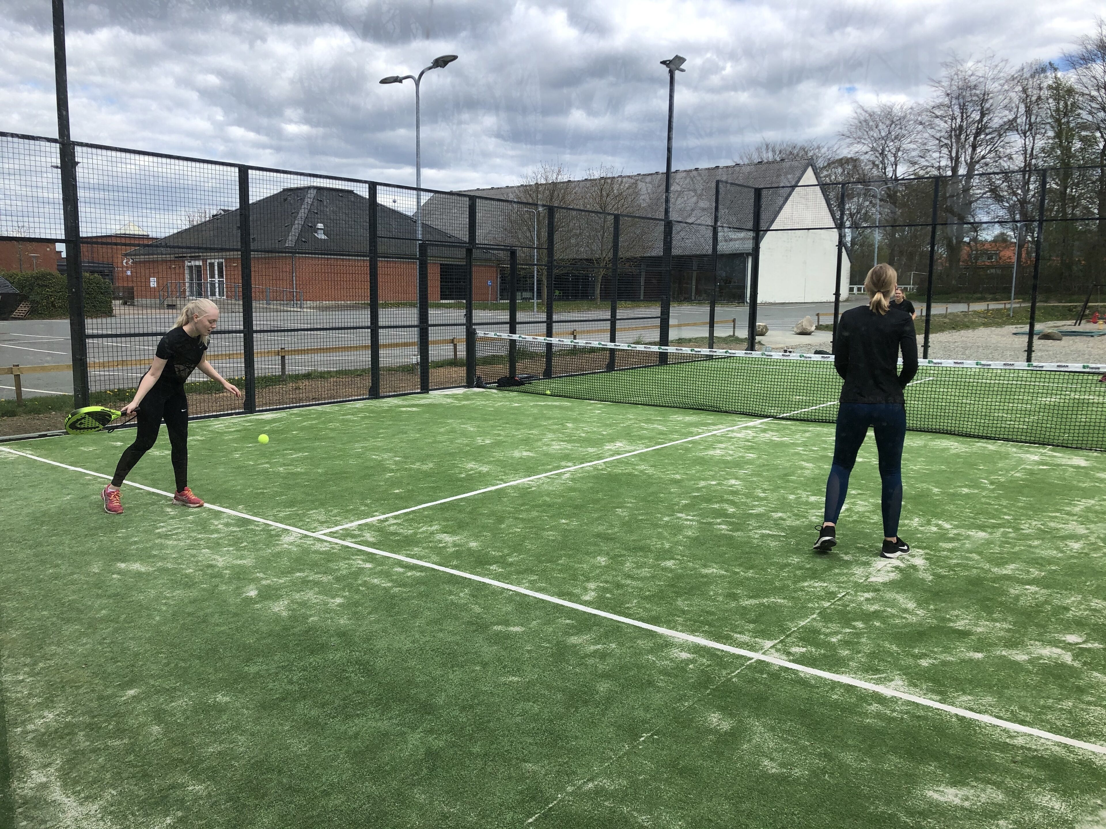 Cancha de tennis a l'aire lliure, amb xarxa i tancada per una valla.
