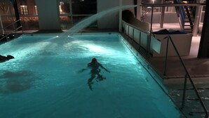 A person swimming in a pool with a water feature.