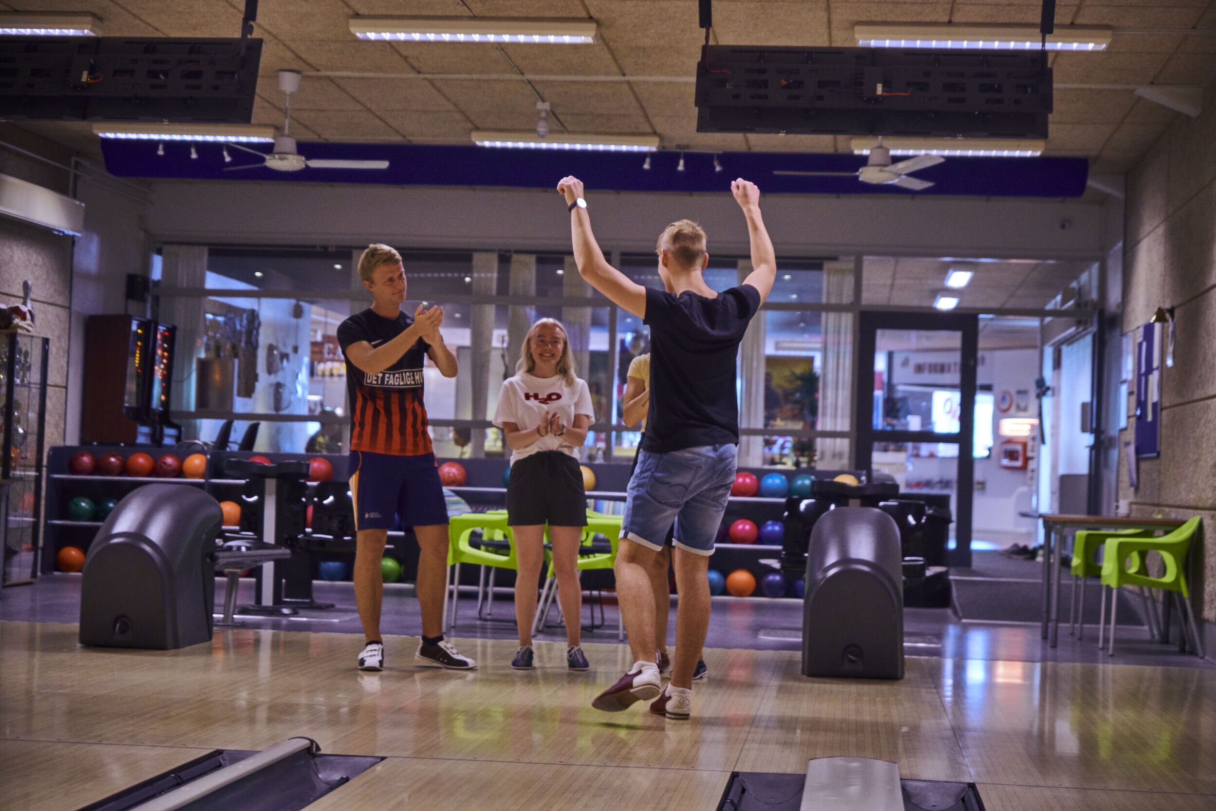 Una pista da bowling con piste di gioco, sedie verdi e palle da bowling.