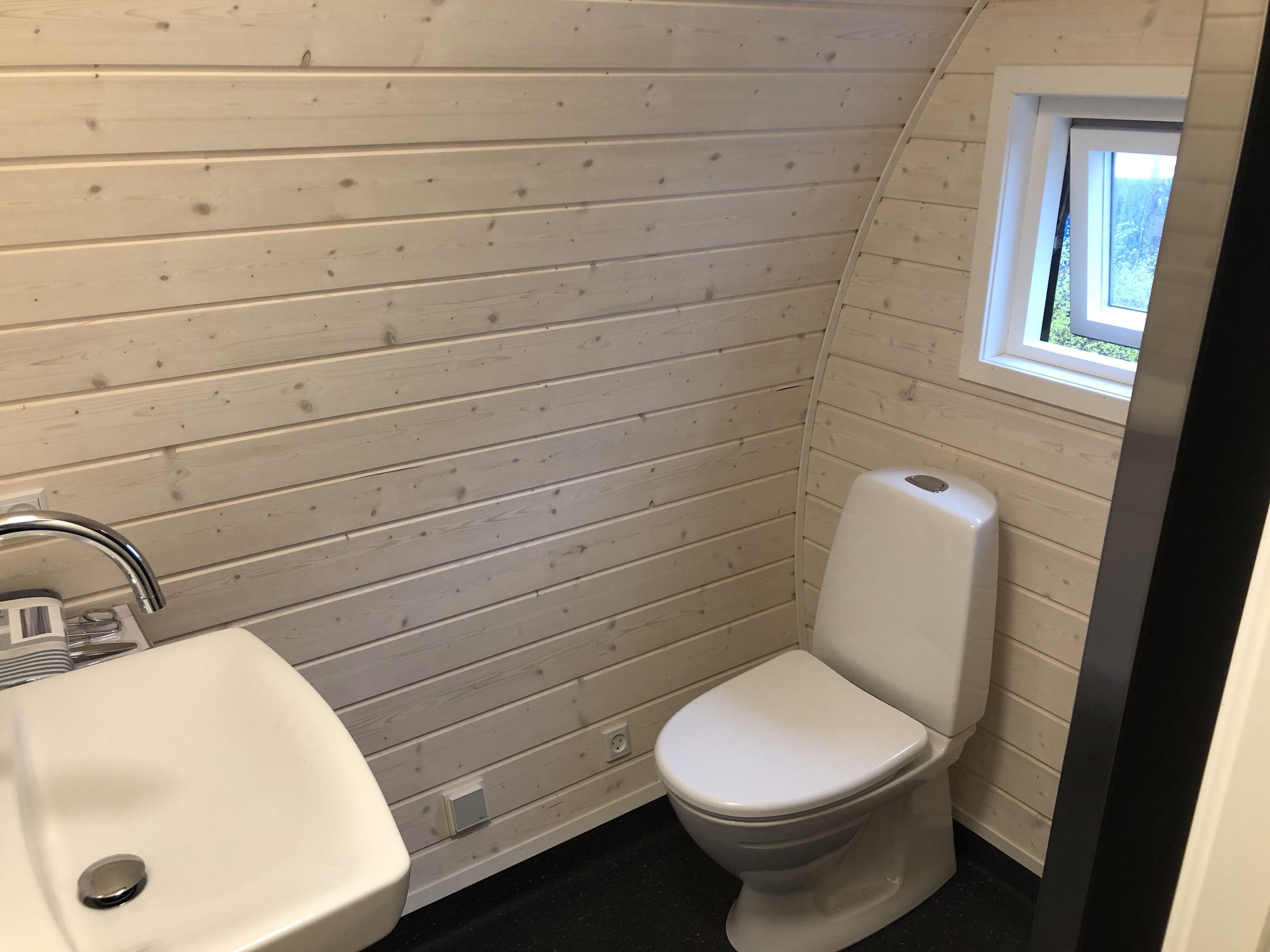 Un baño pequeño y funcional con lavamanos, inodoro y ventana que proporciona luz natural.