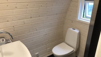 Un baño pequeño y funcional con lavamanos, inodoro y ventana que proporciona luz natural.