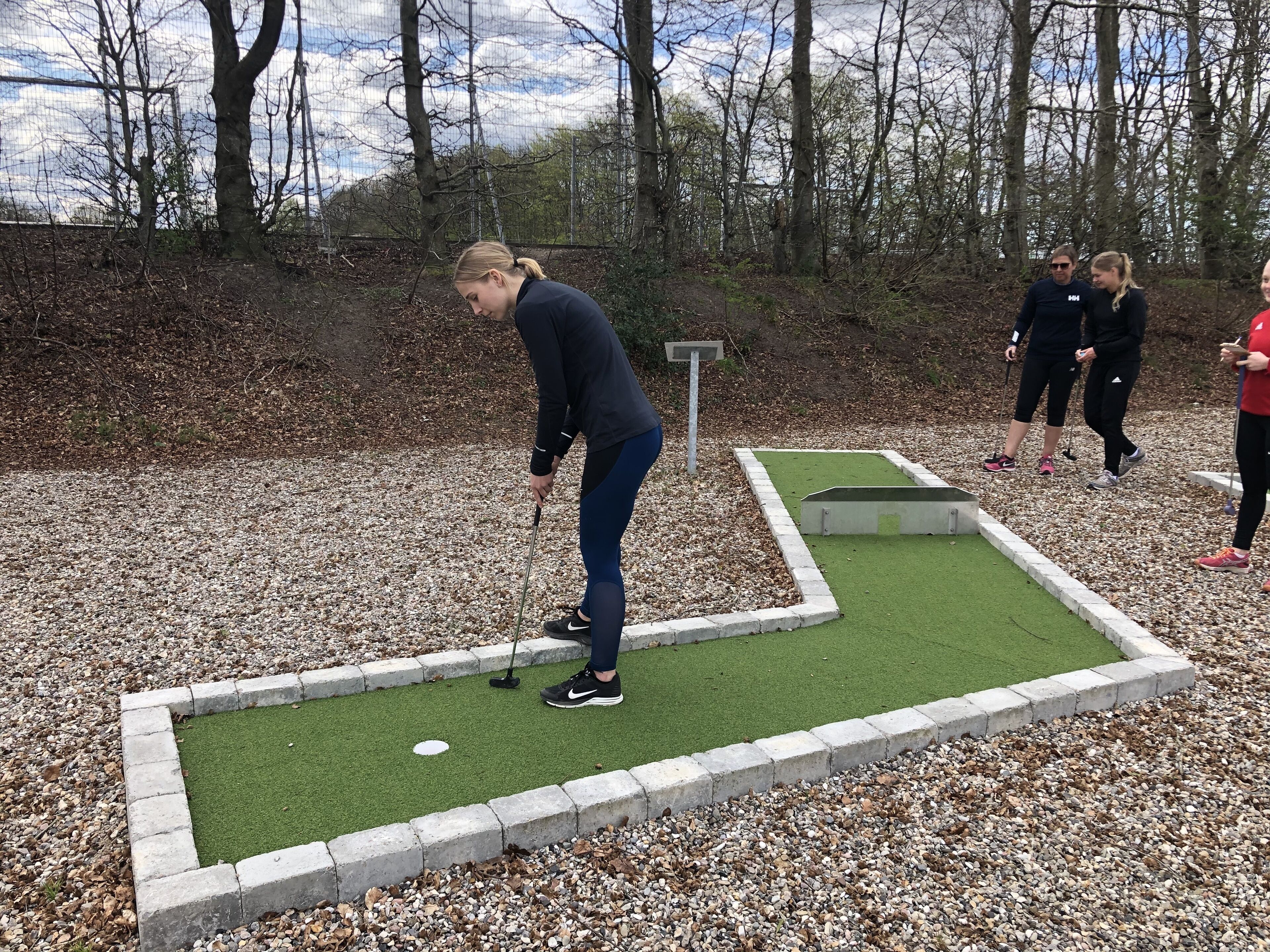 A miniature golf course with a putting green and a small bridge.