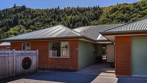 Een tweelaags huis met een metalen dak, een omheinde tuin en een verharde oprit.