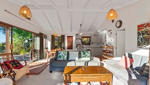 A spacious living area with a sofa, coffee table, and a view of the outdoors. - Ruatotara - Pukawa Holiday Home (Pukawa Bay)
