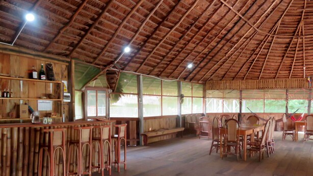 A rustic wooden interior with a high ceiling, wooden furniture, and a bar area. - Intillama Jungle Lodge (Fernando Lores)