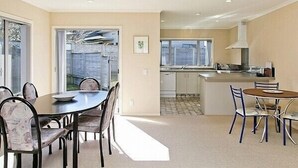 Una cocina moderna con armarios blancos, una campana extractora de acero inoxidable y una ventana con vistas al jardín trasero.