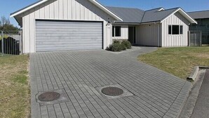 Una casa moderna de un piso con un garaje amplio, un camino de entrada cubierto y un pequeño jardín delantero.