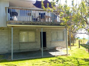 A two-story building with a balcony, a door, and a small garden area. - Relax Lakeside - Five Mile Bay Holiday Home (Five Mile Bay)