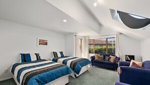 Ein Schlafzimmer mit zwei Betten, einem Schlafsofa und einem Fenster mit Vorhängen.