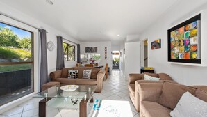 Ein modernes Wohnzimmer mit einem Glastisch, zwei Sofas und einem Essbereich mit Tisch und Stühlen.