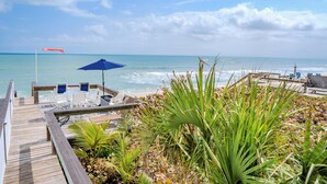 Eine Holzterrasse mit Sitzgelegenheiten und Blick auf das Meer.