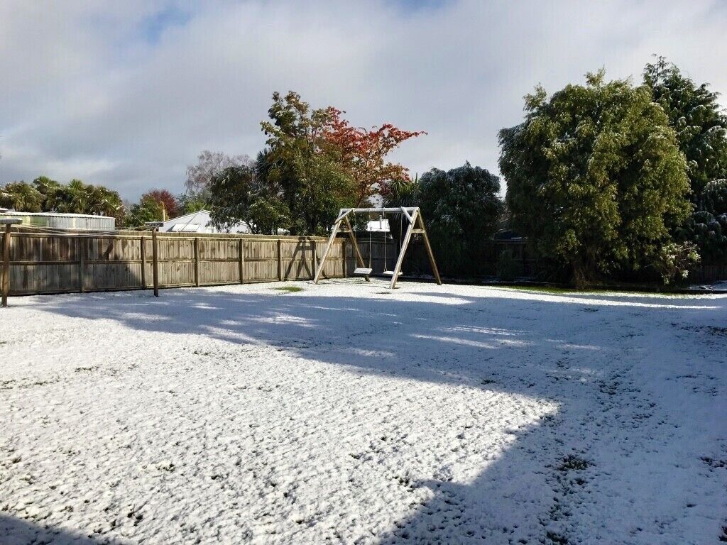 Ein mit Schnee bedeckter Garten mit Schaukel und Holzzaun.