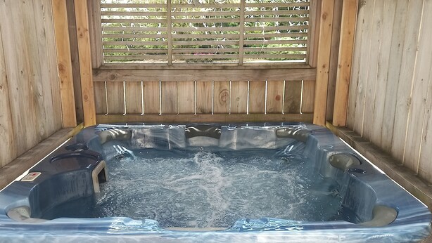 A spa pool with wooden walls and a window with blinds. - Snowed Inn - Ohakune (Miro) Holiday Home (Ohakune)