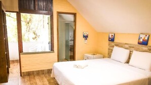 Un dormitorio con cama, mesita de noche, ventana y puerta.