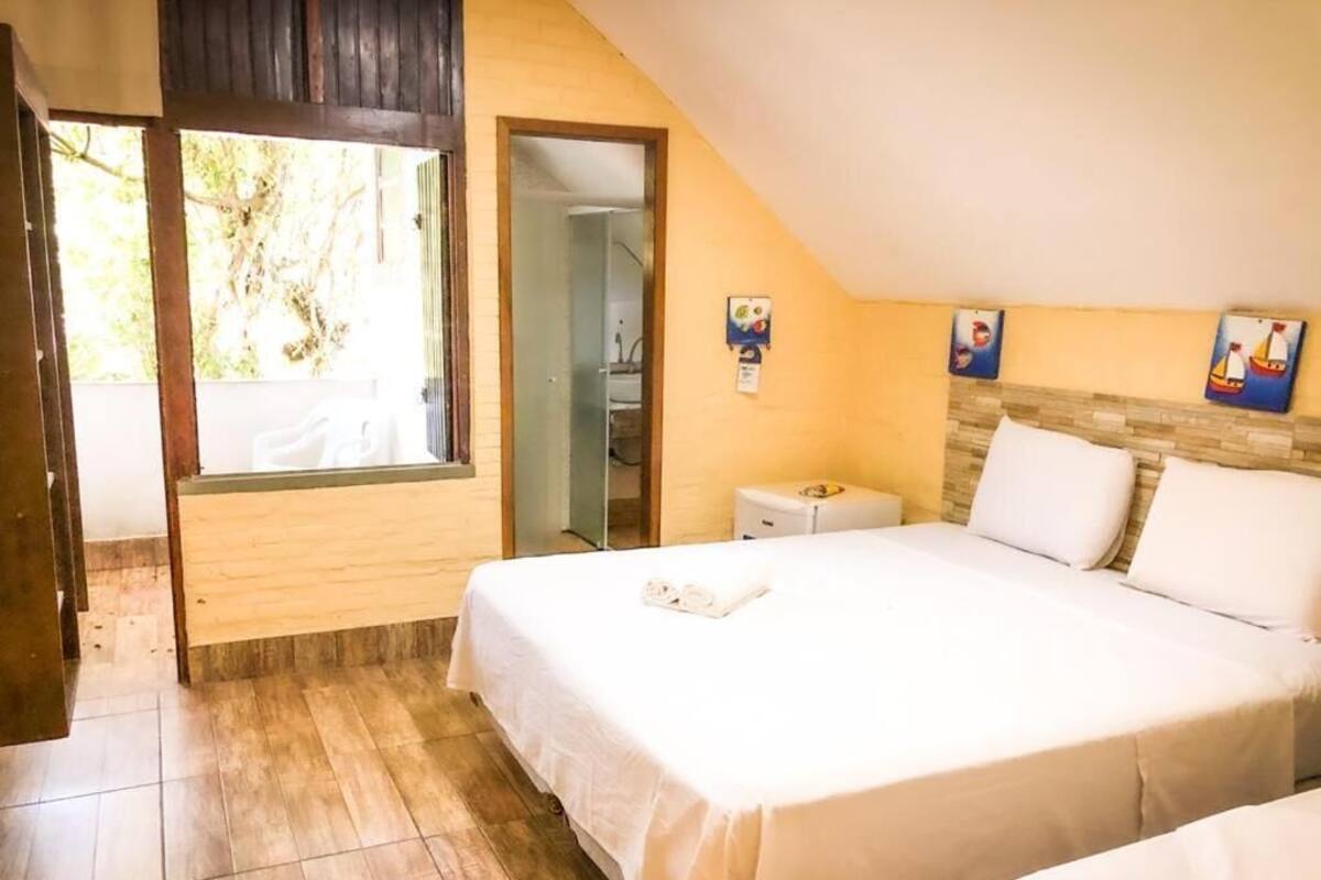 A bedroom with a bed, a bedside table, a window, and a door.