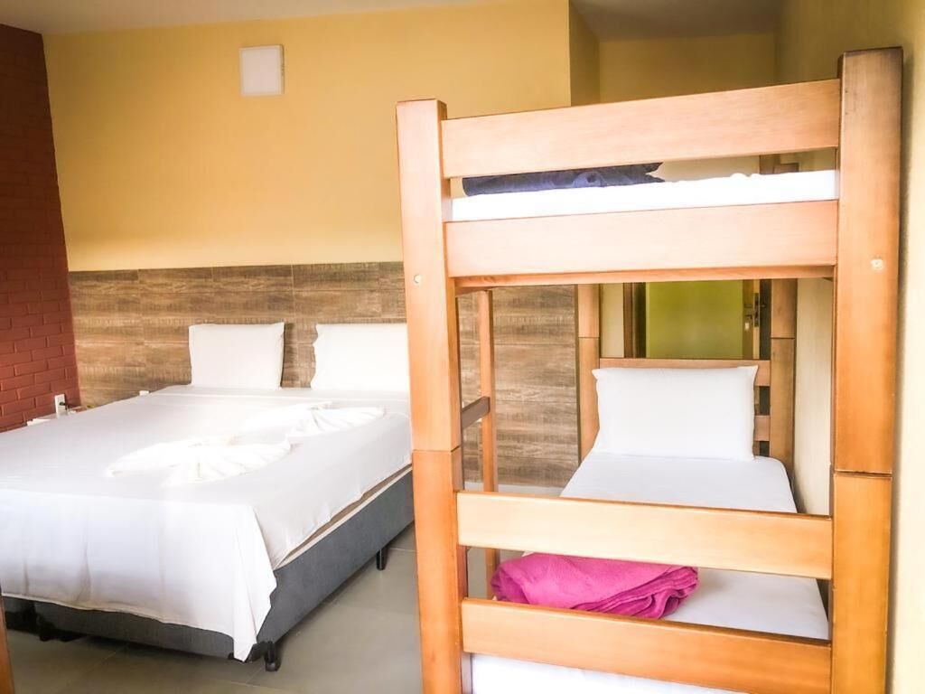 A hotel room with two beds, one with a wooden headboard and the other with a metal frame.
