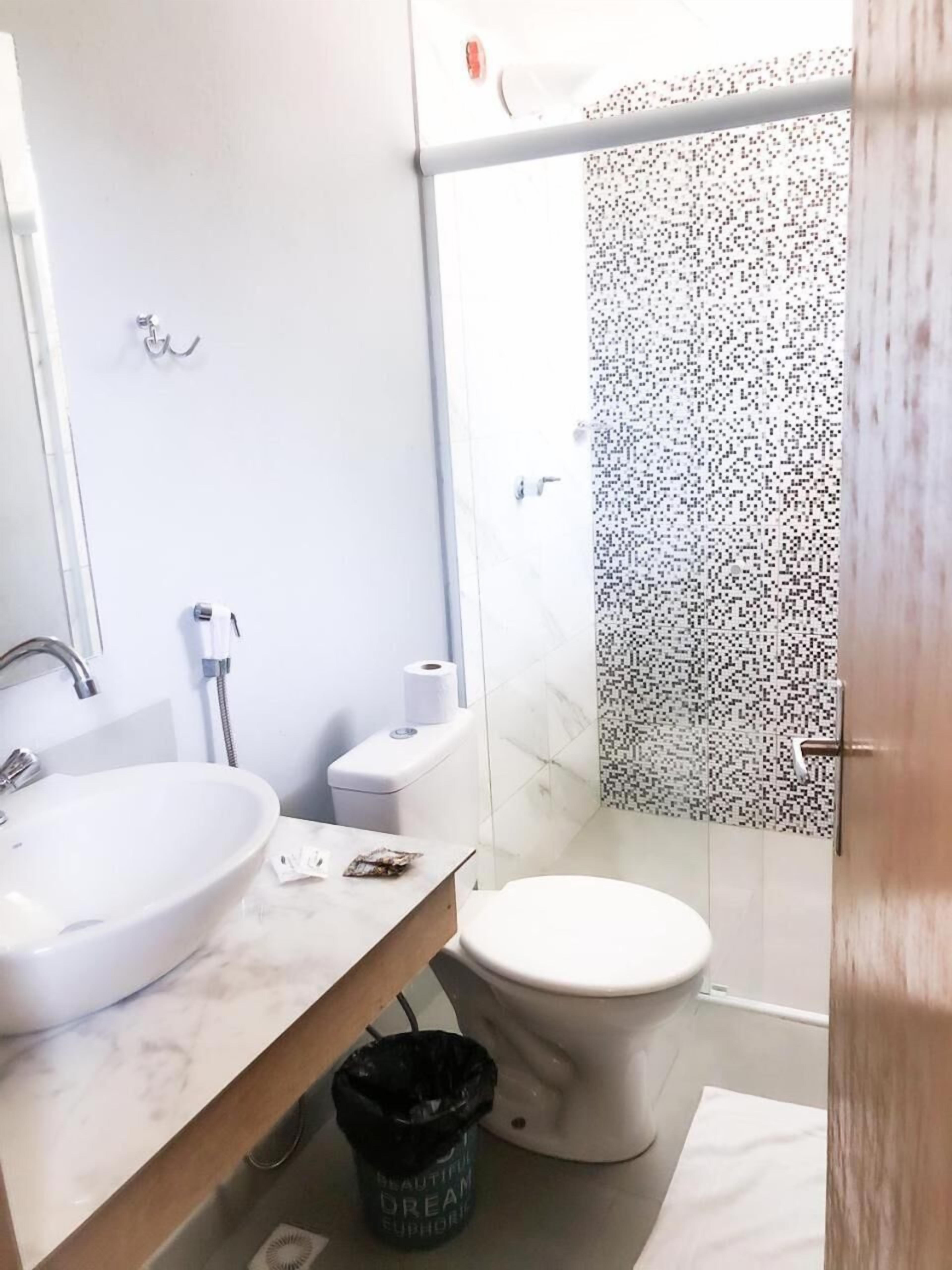 A modern bathroom with a white sink, toilet, and shower.
