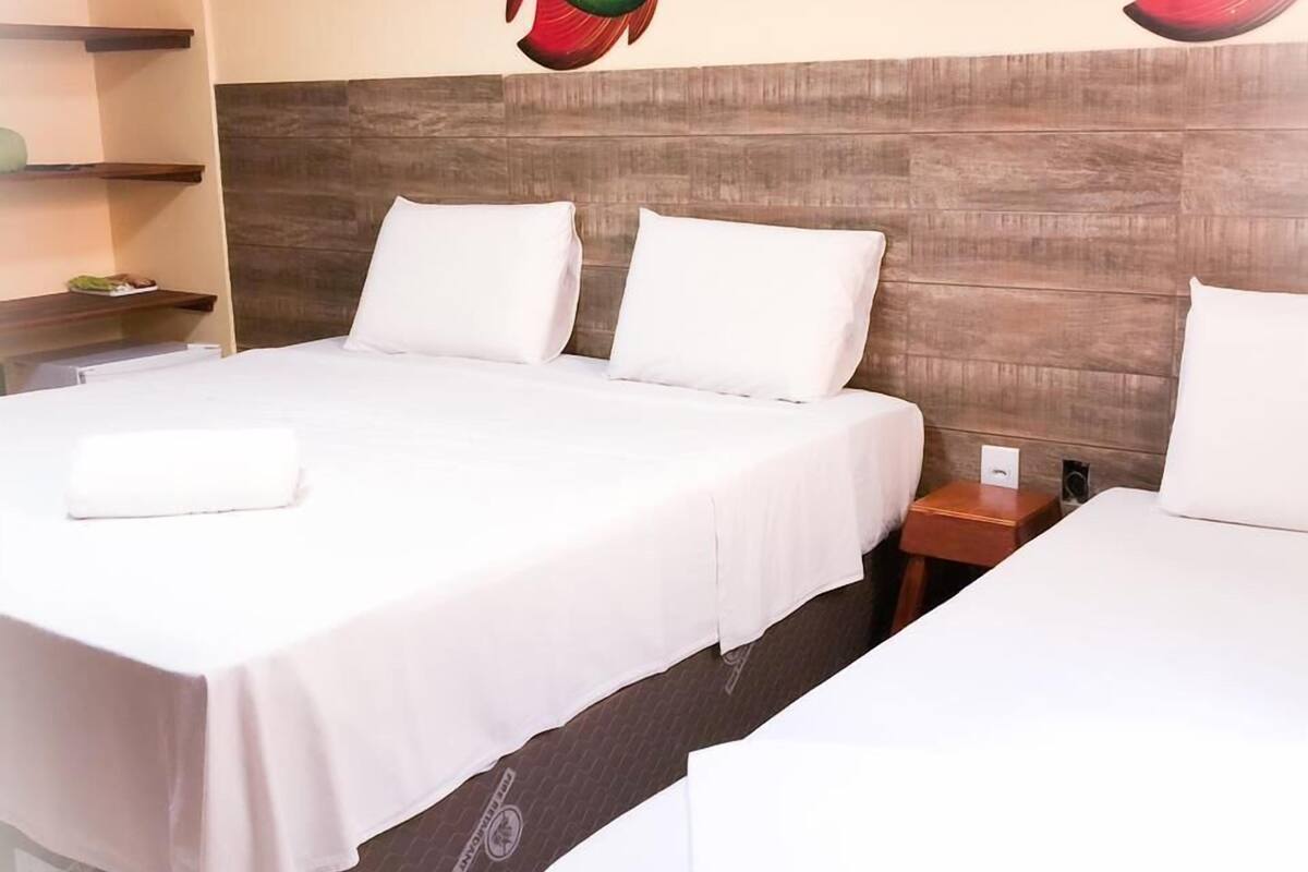 A hotel room with two beds, a wooden headboard, and a wall with two large fish paintings.