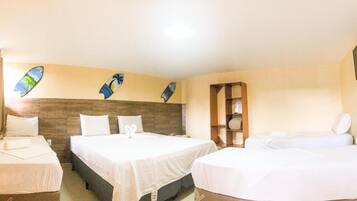 Habitación de hotel con dos camas, cabecera de madera, televisor y estante con toallas.