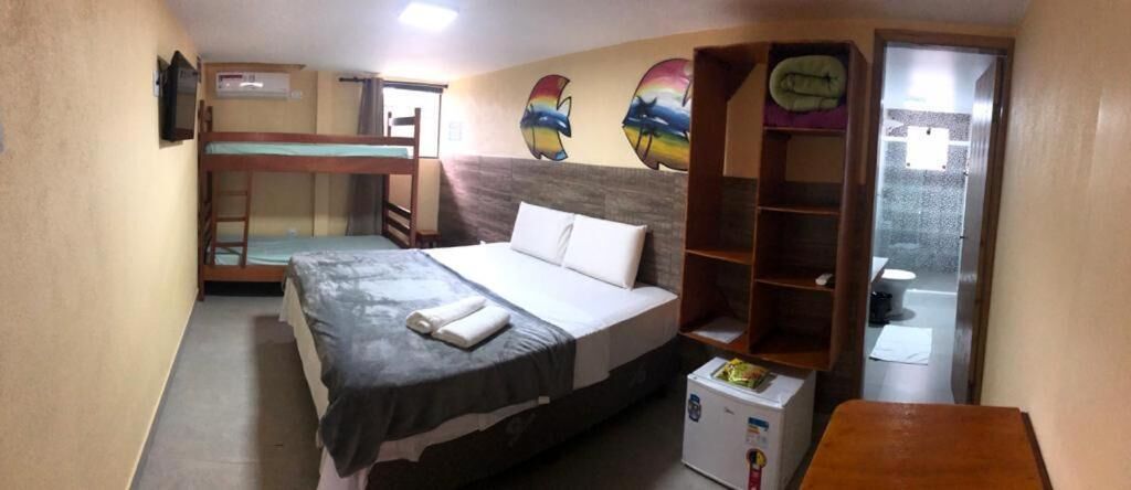 A compact hotel room with a bunk bed, a small desk, a refrigerator, and a bathroom visible through an open door.