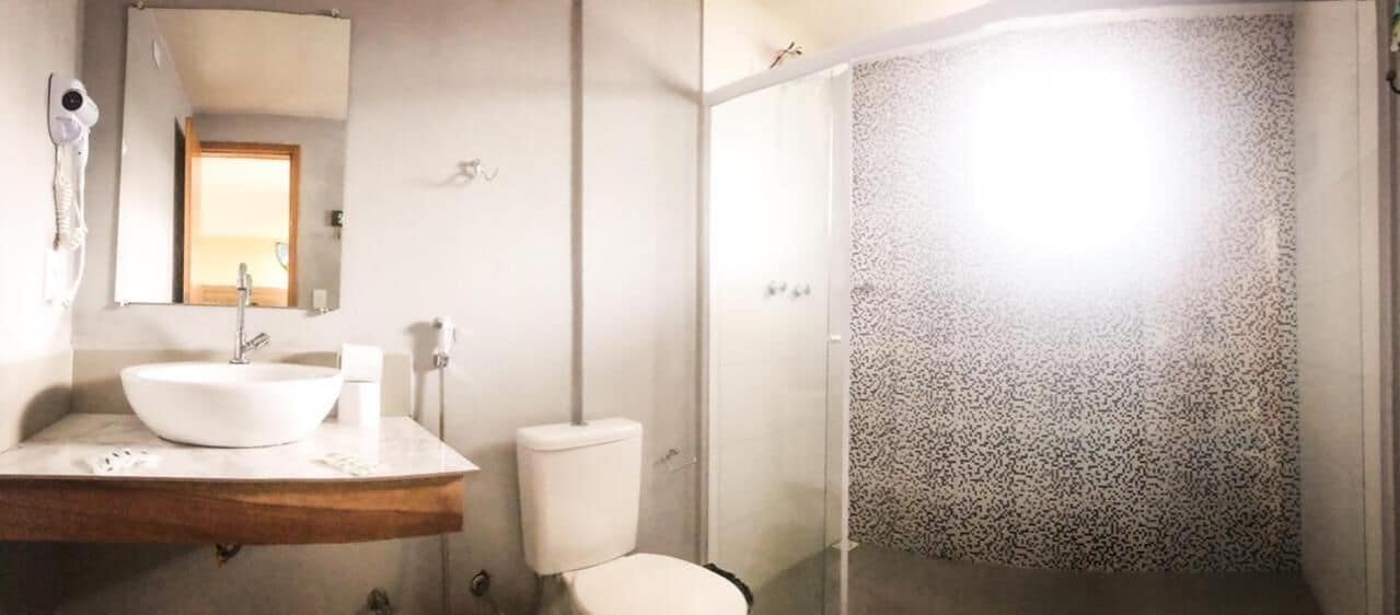 A bathroom with a white sink, mirror, and toilet.