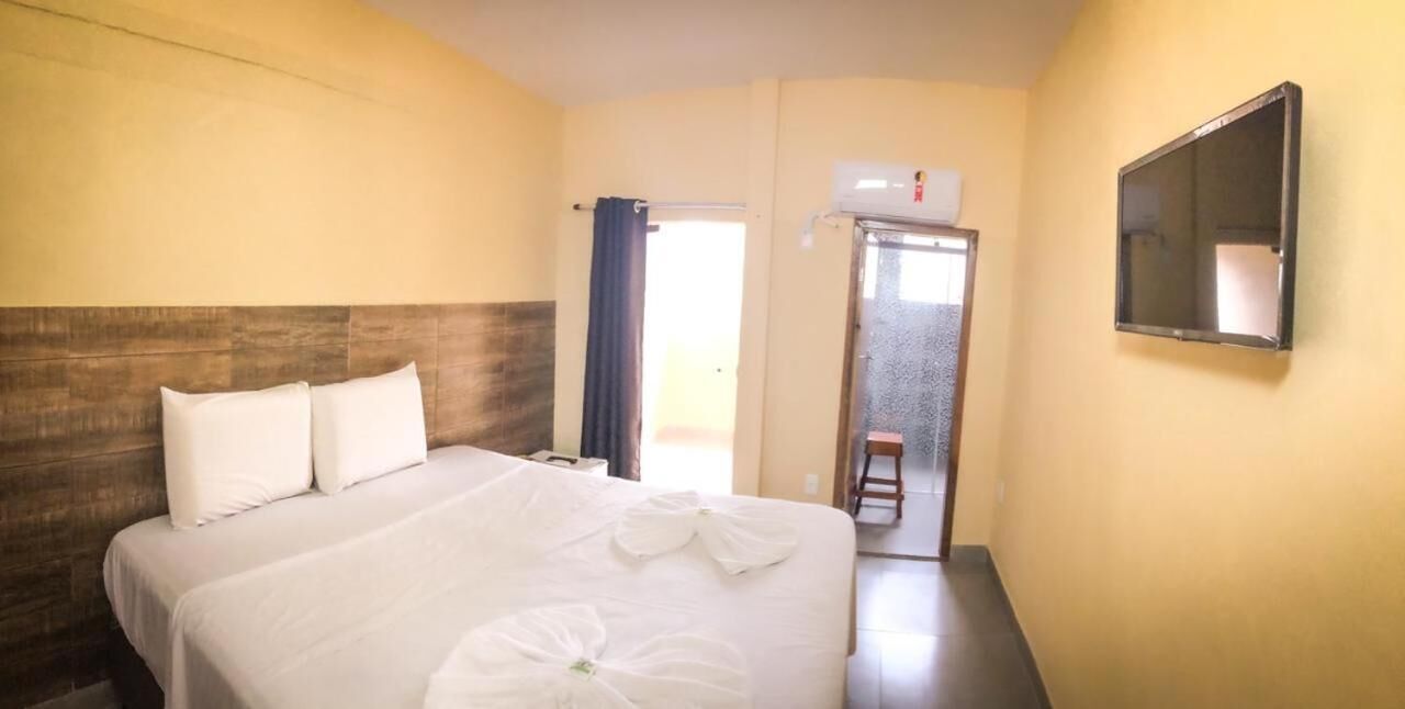 Habitación de hotel con cama, televisor de pantalla plana y puerta que da a un balcón.