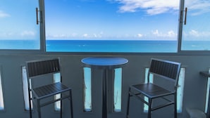 Un balcón con dos sillas y una mesa, con vistas a un mar azul y despejado.