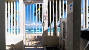 Entrada en la playa con puerta cerrada, vista al océano y letrero de grifo.
