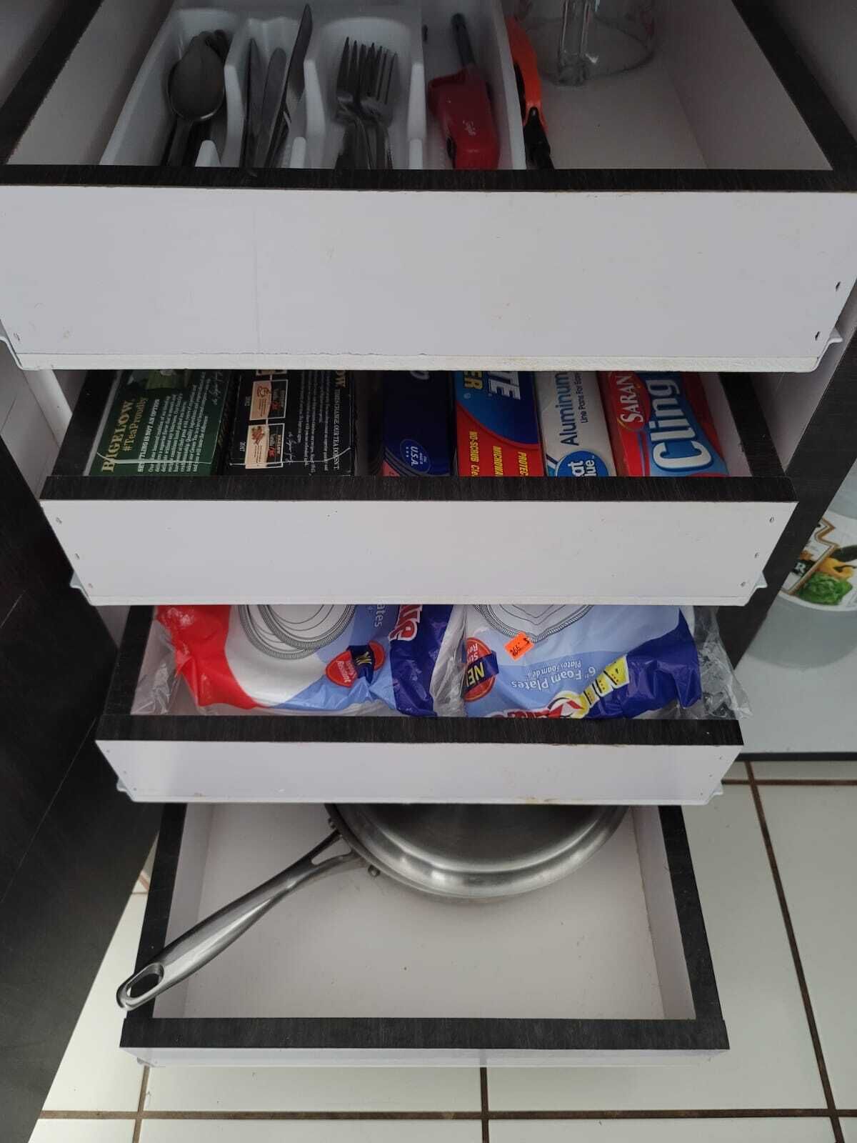 Eine Küchenschublade mit Besteck, Reinigungsmitteln und einem Topf.