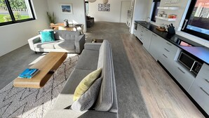 A modern living room with a grey sofa, a wooden coffee table, and a large woven pendant light. - Modern, large, open plan 1 bedroom apartment (Surfdale)