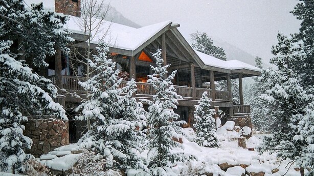 A log cabin with a stone foundation, wooden deck, and snow-covered landscape. - Eagles Rest:Mountain views>Huge home>Hiking (#23-ZONE3439) (Estes Park)